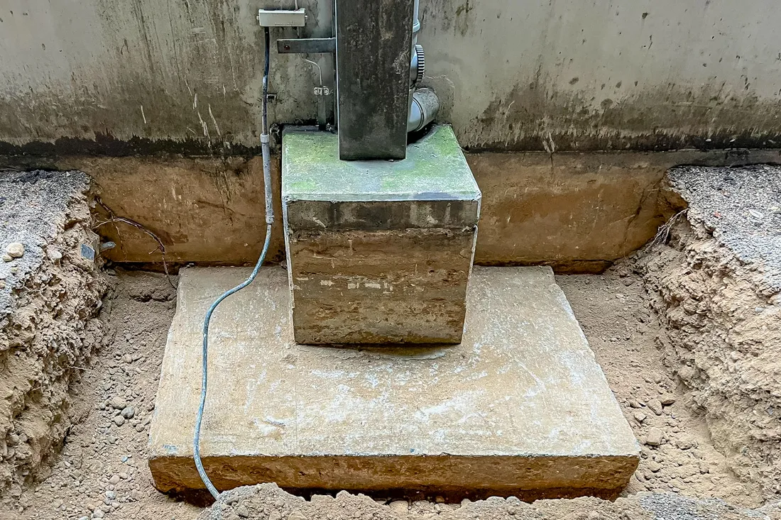 Statische Unterfangung einer Stütze durch Resintech Augsburg: Freigelegtes Betonfundament in einer Baugrube zur Statik-Sicherung.