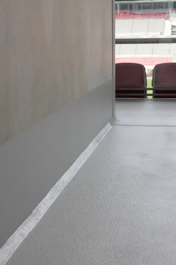 Frisch versiegelte Bodenfläche und Wandanschluss in einem Stadiongang, fachgerecht ausgeführt von Resintech.