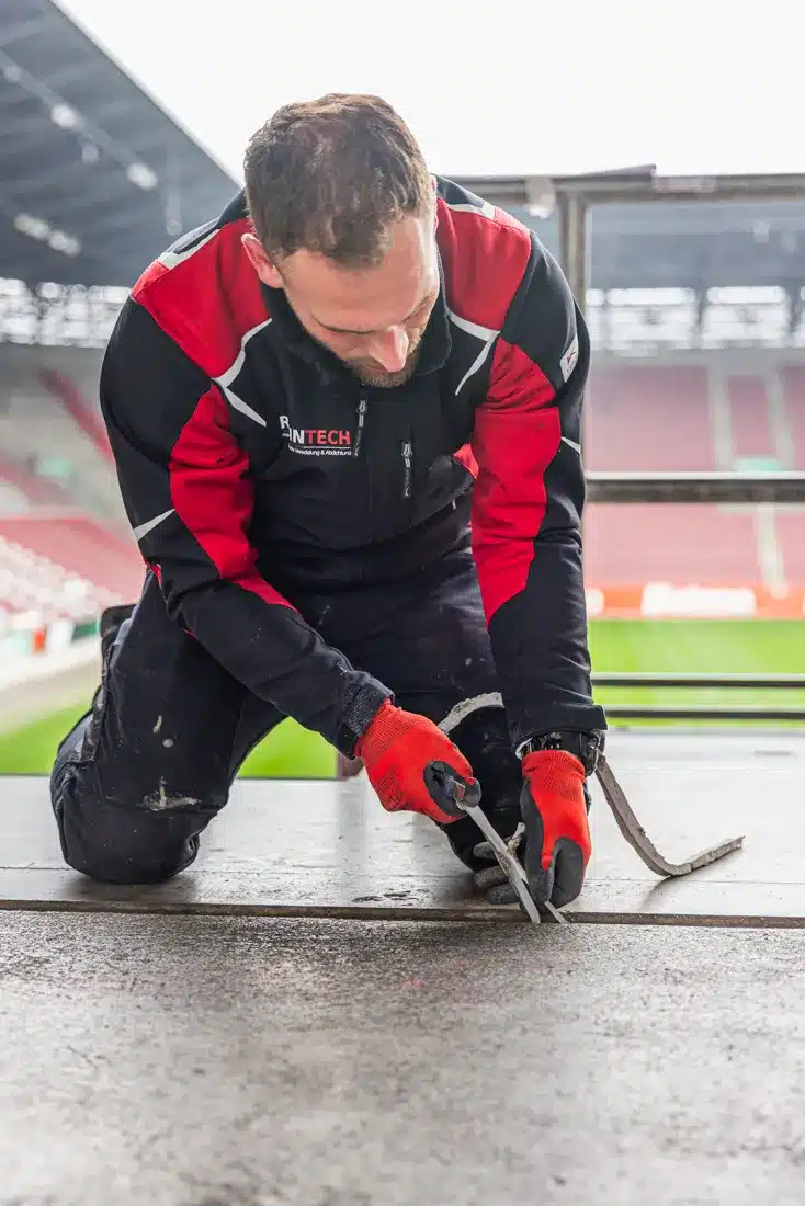 Sanierungsexperte von Resintech bei Abdichtungsarbeiten an einer Bodenfuge im Stadion Augsburg.