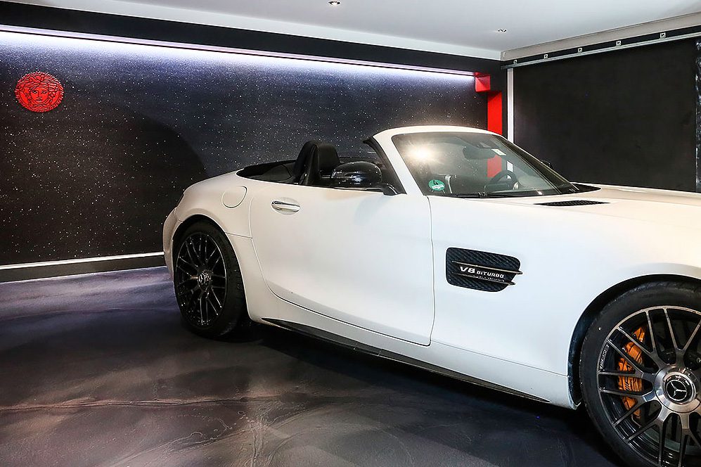 Exklusive Garagenveredelung: Weißer Sportwagen auf einem nahtlosen Design-Harzboden vor einer Wandgestaltung im Sternenhimmel-Look.