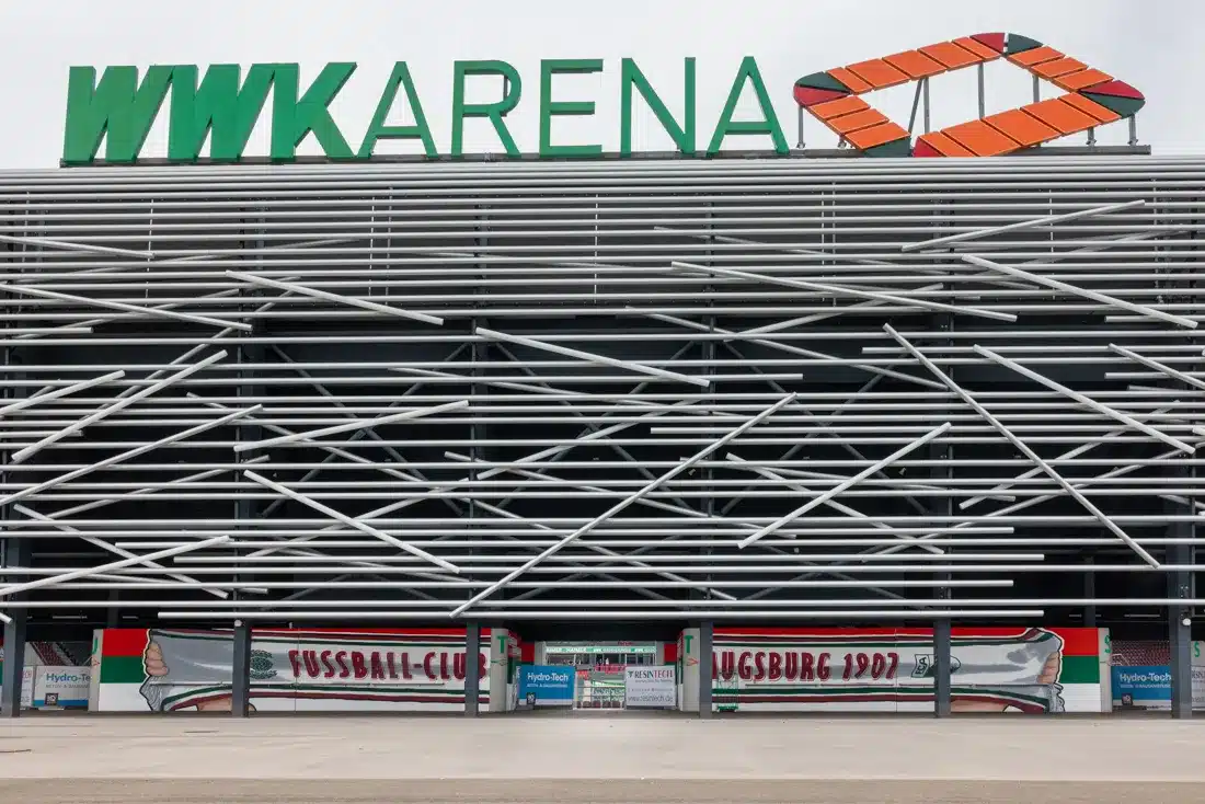 Außenansicht der WWK Arena Augsburg mit markanter Rohr-Fassade und dem Firmenlogo von Resintech im Eingangsbereich.