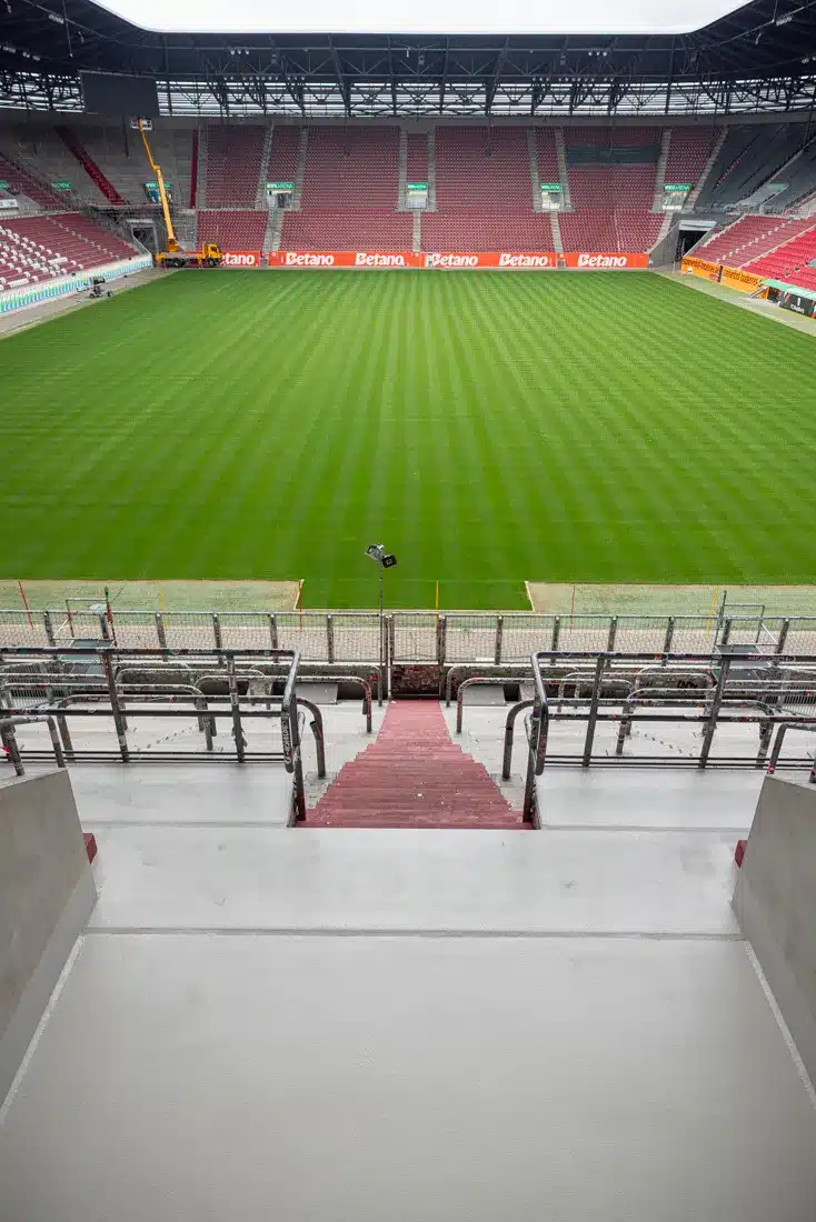 Blick von einer sanierten Tribünenplattform auf den Rasen der WWK Arena – Bodenschutz und Beschichtung aus Augsburg.